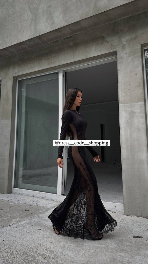 Andrea indossa un long dress nero nero aderente, caratterizzato da un design elegante e sensuale.
Presenta maniche lunghe e una scollatura rotonda.